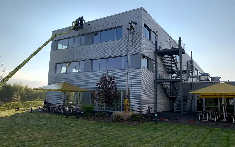 Bürogebäude mit Metallfassade, zwei Hubarbeitsbühnen sind an der Fassade im Einsatz